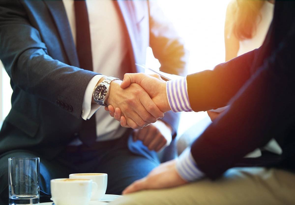 Business professionals shaking hands across a meeting table